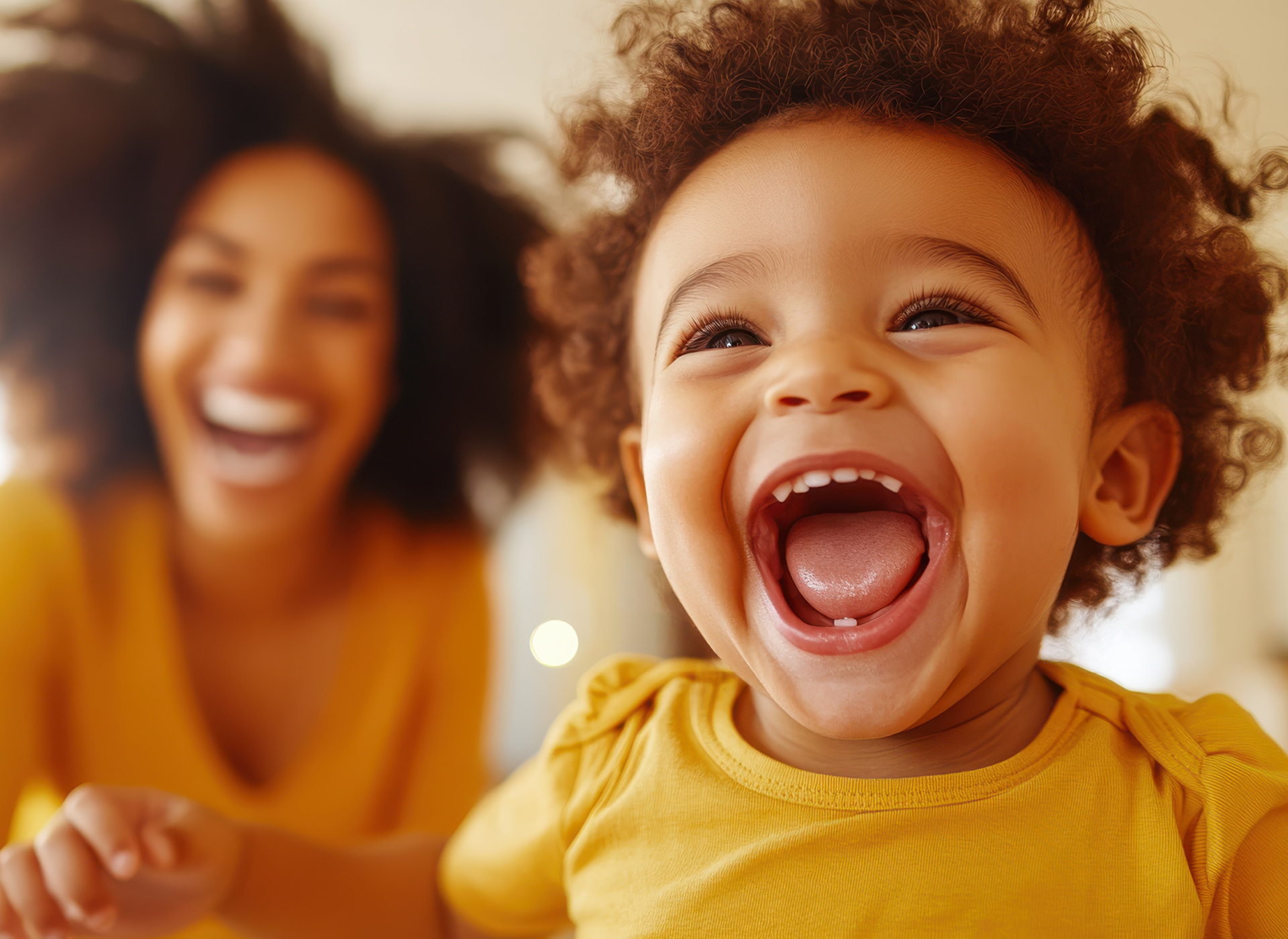 smiling baby in foreground, blurred mom in background