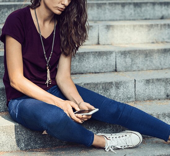 Teen girl sitting on stairs looking at phone